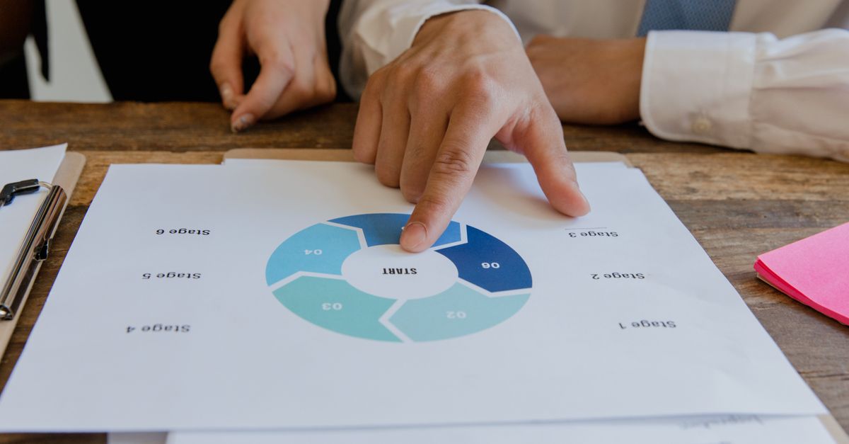 Close-up of hands pointing to a circular business strategy plan on paper.