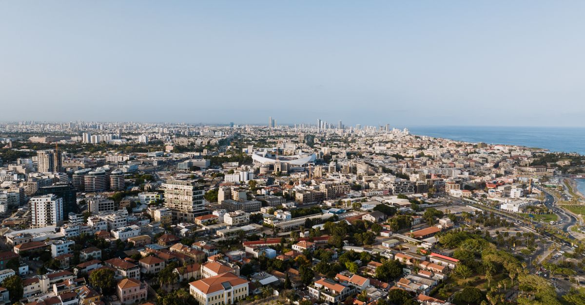 Expansive aerial cityscape of Tel Aviv-Yafo with coastal views, captured in daylight.